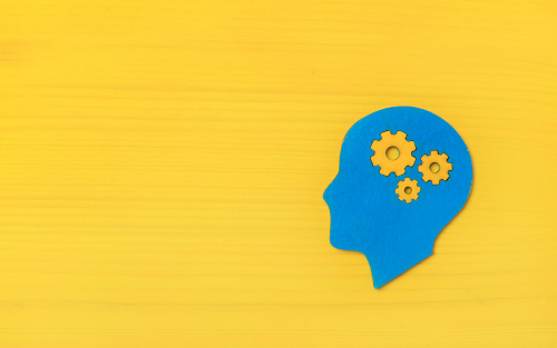 Blue silhouette of a head with yellow gears inside, set against a yellow background.