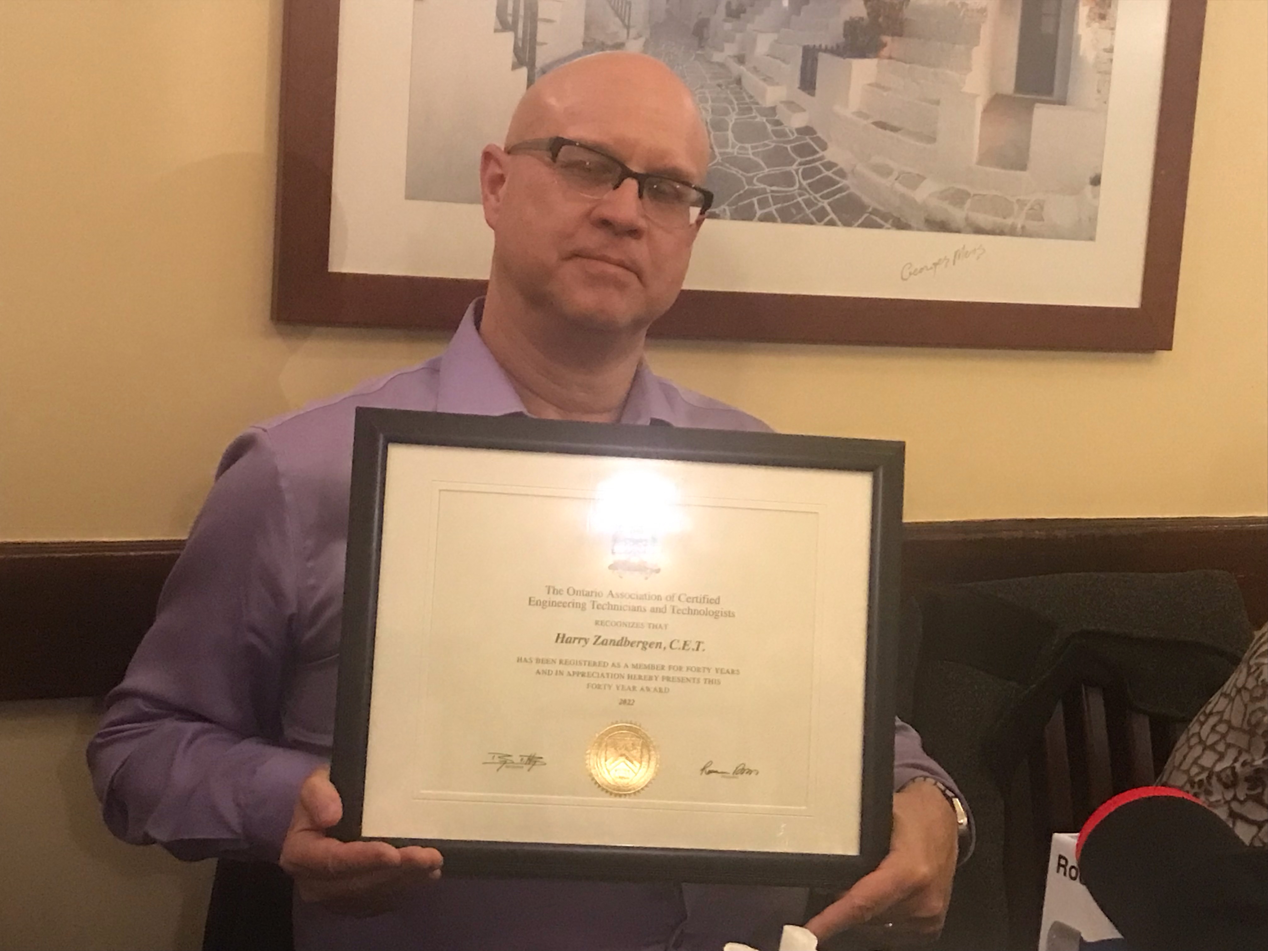 40 year Man wearing glasses holding an award