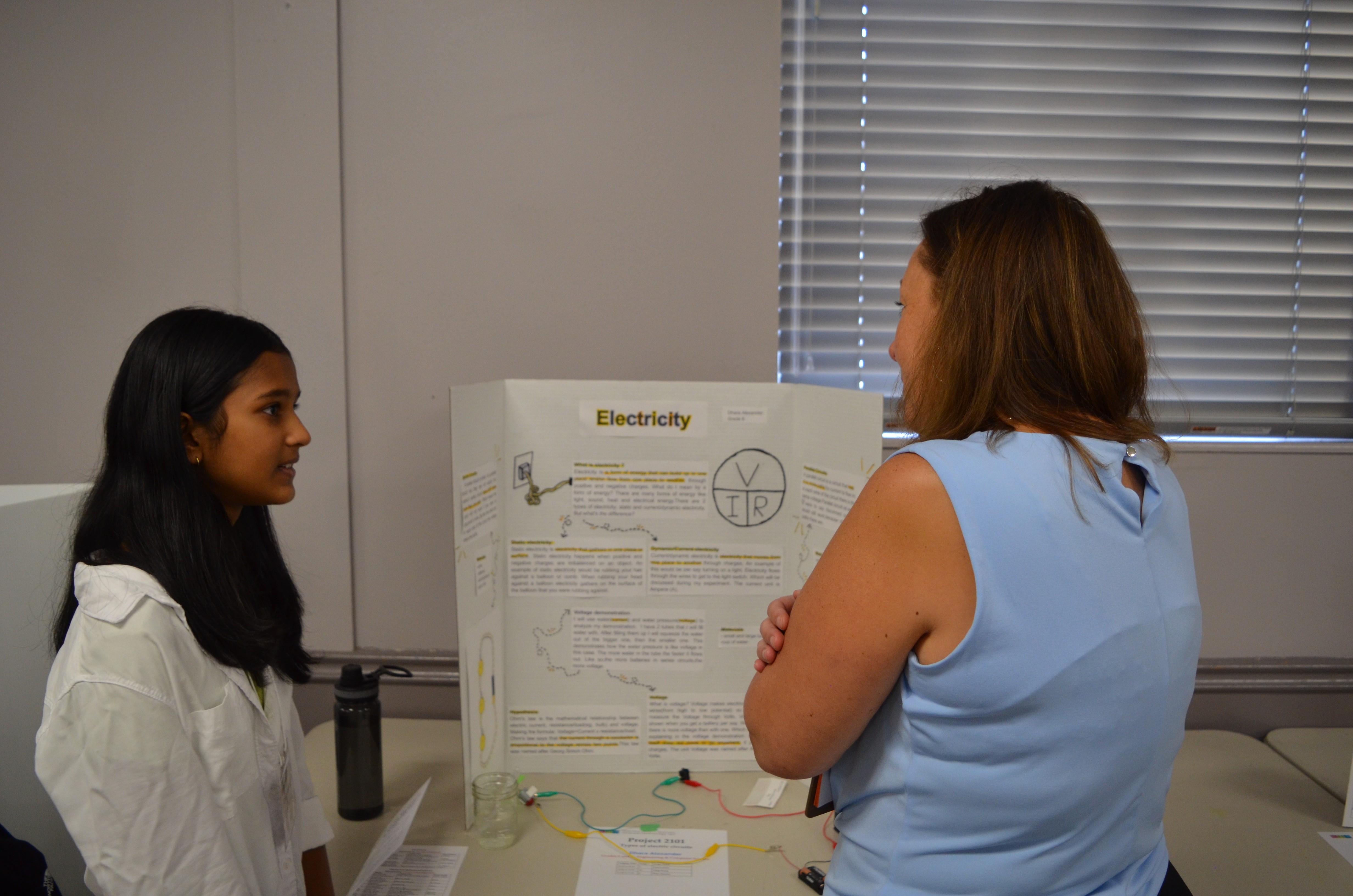 science fair 3 A women looking a girl's science project