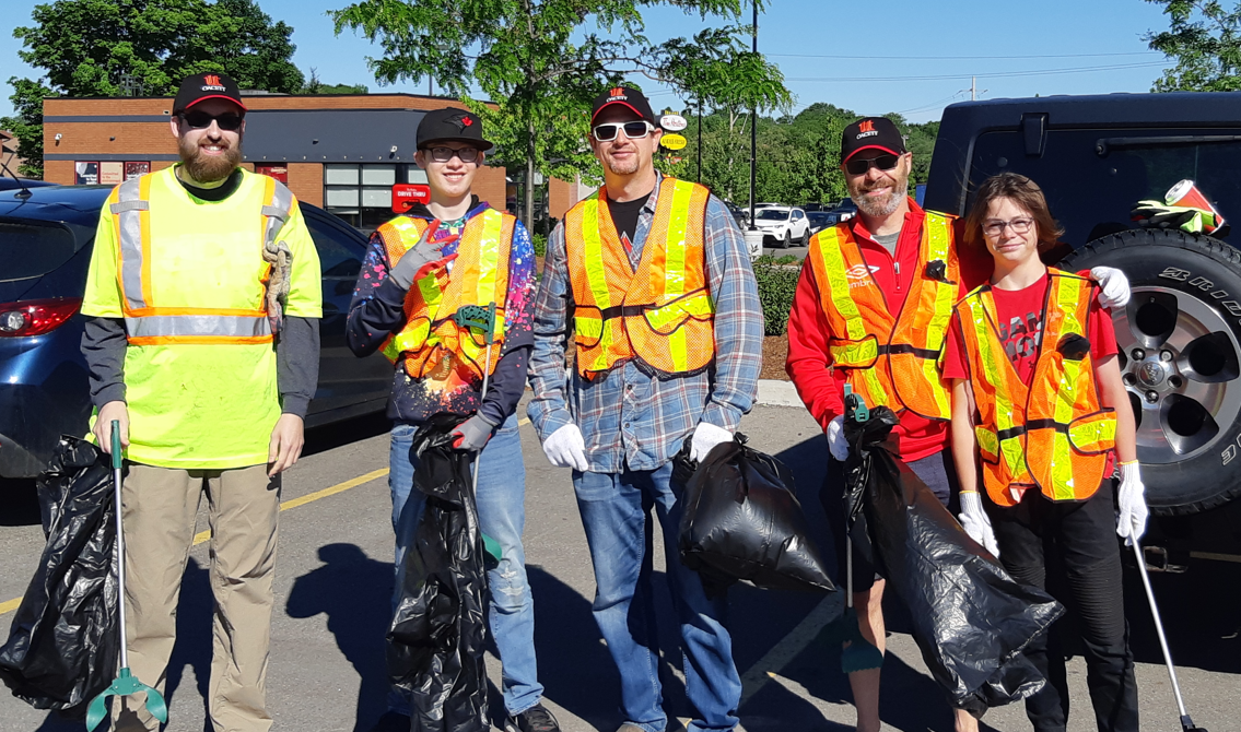 road cleanup men and boys in reflective vests holding garbage bags